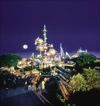 Guests explore Tomorrowland at Disneyland as vibrant, futuristic lights illuminate the night and modern architecture shines.