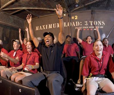 Guests thrill-seeking on the Tower of Terror, arms up and screaming in excitement, sporting red uniforms and casual attire.