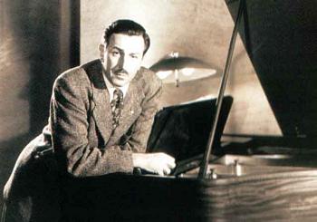 Walt Disney leaning on a piano