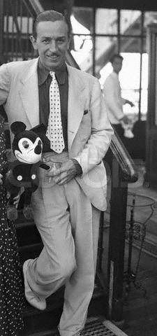 A classic Disney executive beams on a grand staircase, proudly displaying a vintage Mickey Mouse doll—a nod to Disney legacy magic.