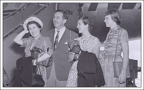 Guests dressed in retro outfits smile by a vintage plane, echoing the timeless adventure vibes of classic Disney parks.