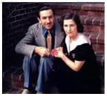 A couple sits together on the steps at Universal Studios, holding hands and smiling toward the camera.