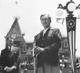 A speaker addresses guests at the microphone in front of Disneyland’s famous Main Street station and signature clock tower.