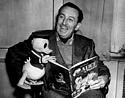 A Disney fan beams, showing off a Donald Duck plush and comic, sharing the whimsical joy of classic Disney collectibles.