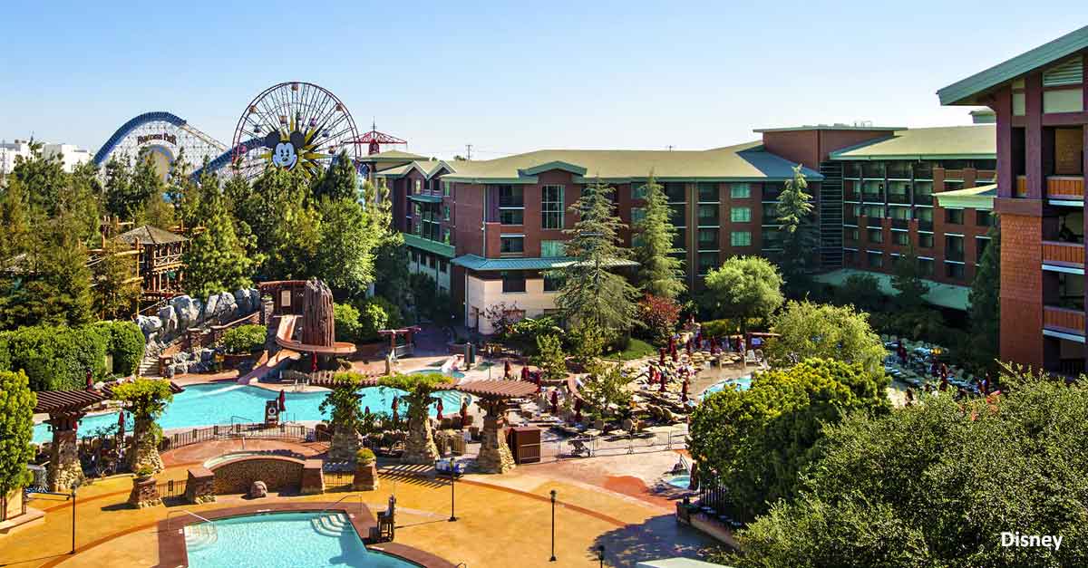 Aerial view of Disneyland Resort’s sparkling pools, lush grounds, and iconic theme park attractions in the distance.