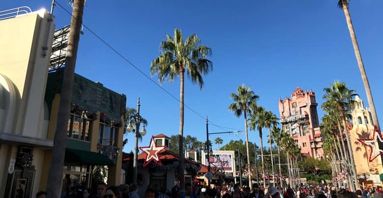 Guests stroll down Disney's palm-lined Main Street, festive with holiday decor and a view of the iconic Hollywood Tower Hotel.