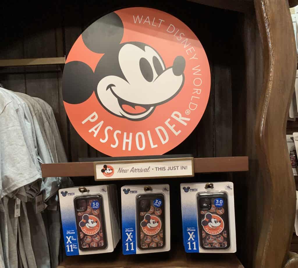Disney World Passholder sign featuring Mickey Mouse above iPhone X/11 cases with Mickey designs, spotlighting annual passes.