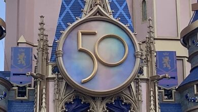A sparkling golden "50" anniversary sign shines on Cinderella Castle, celebrating Disney World's milestone in magical style.