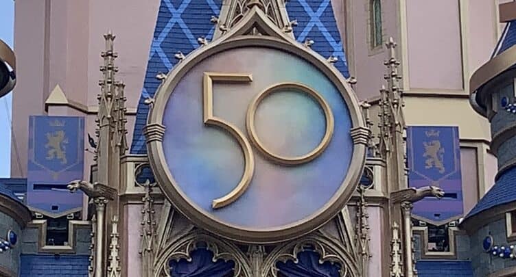 A sparkling golden "50" anniversary sign shines on Cinderella Castle, celebrating Disney World's milestone in magical style.