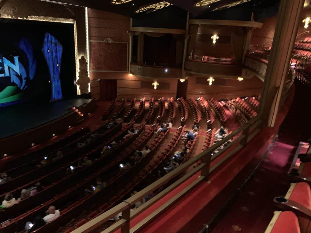 The Walt Disney Theatre on the Disney Fantasy, with signature red seats and a lively audience awaiting the next spectacular show.