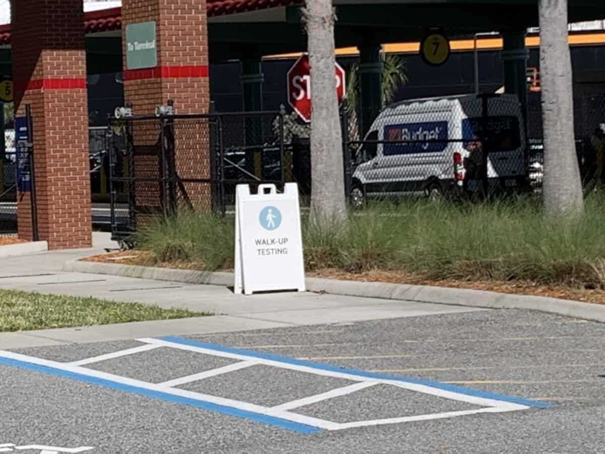 A "WALK-UP TESTING" sign on the sidewalk, echoing the neatly arranged queues outside Disney Fantasy’s embarkation entrance.