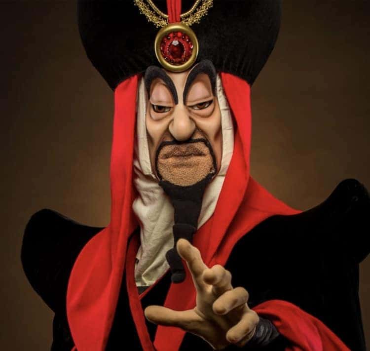 A cartoon villain in a striking red and black outfit with a tall hat entertains guests at Villains Nite, Disneyland After Dark.