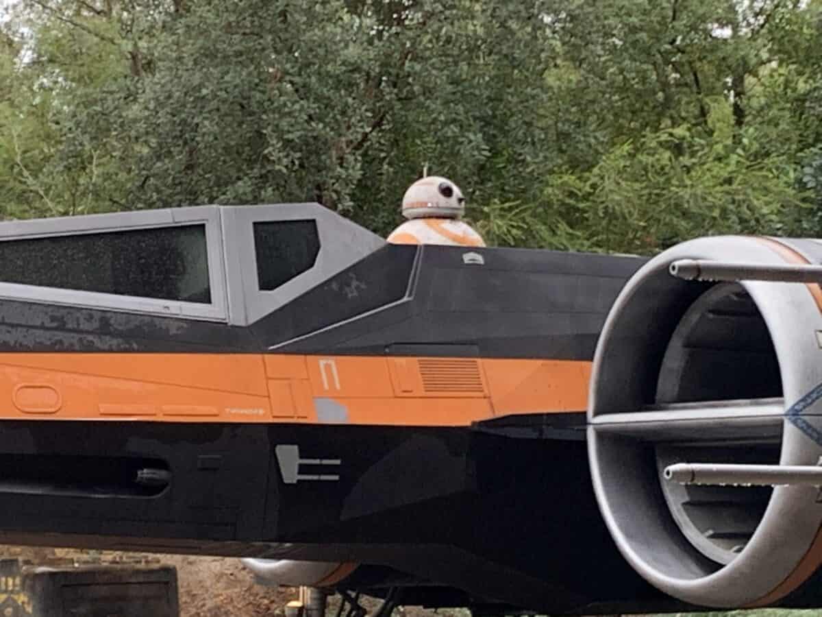 X-wing with BB-8 behind the cockpit, nestled among trees, just like the iconic centerpiece at Star Wars: Galaxy’s Edge.