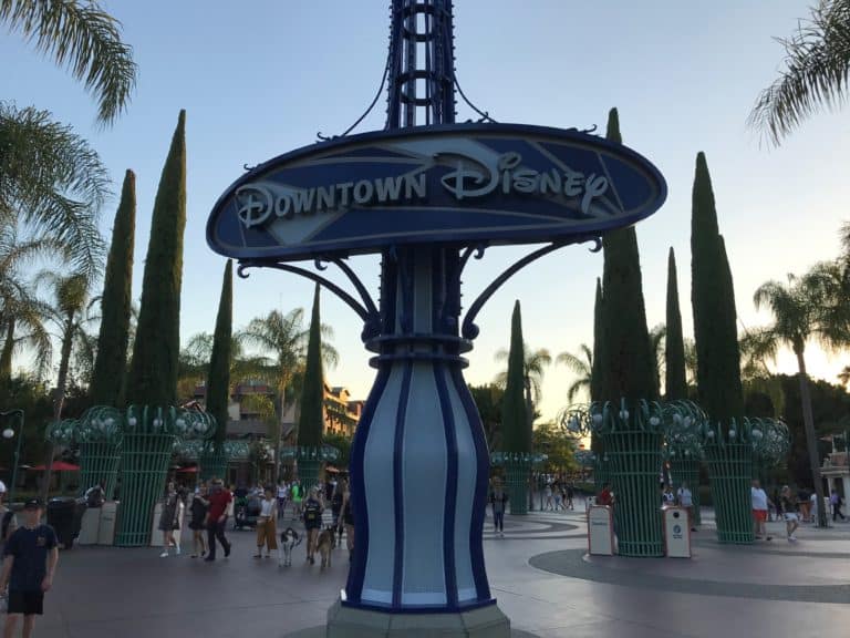 The vibrant Downtown Disney sign welcomes guests amid palm trees, bustling with visitors enjoying the Disneyland Resort excitement.