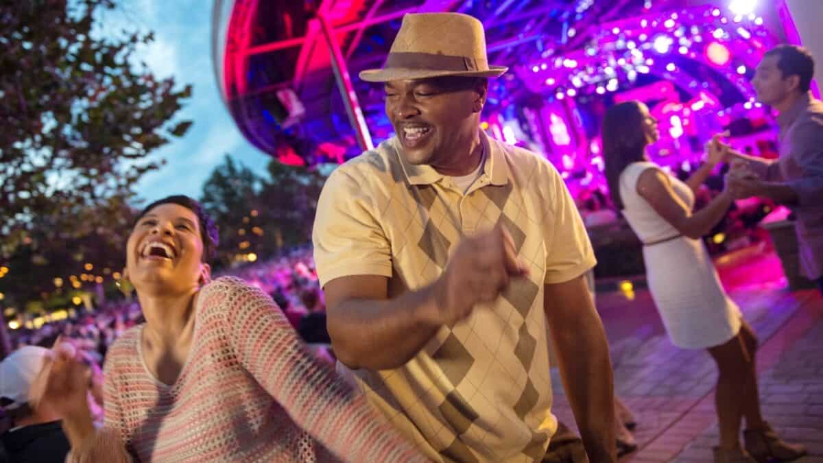 Guests dance and smile under vibrant lights at EPCOT, enjoying Garden Rocks Artists’ energetic live show during a festival evening.