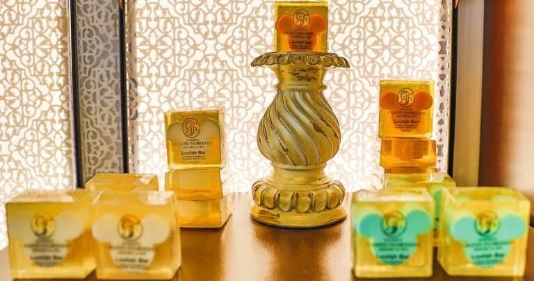 Glistening gold-wrapped soaps displayed like magical treasures on a grand stand, reminiscent of Main Street shop windows.