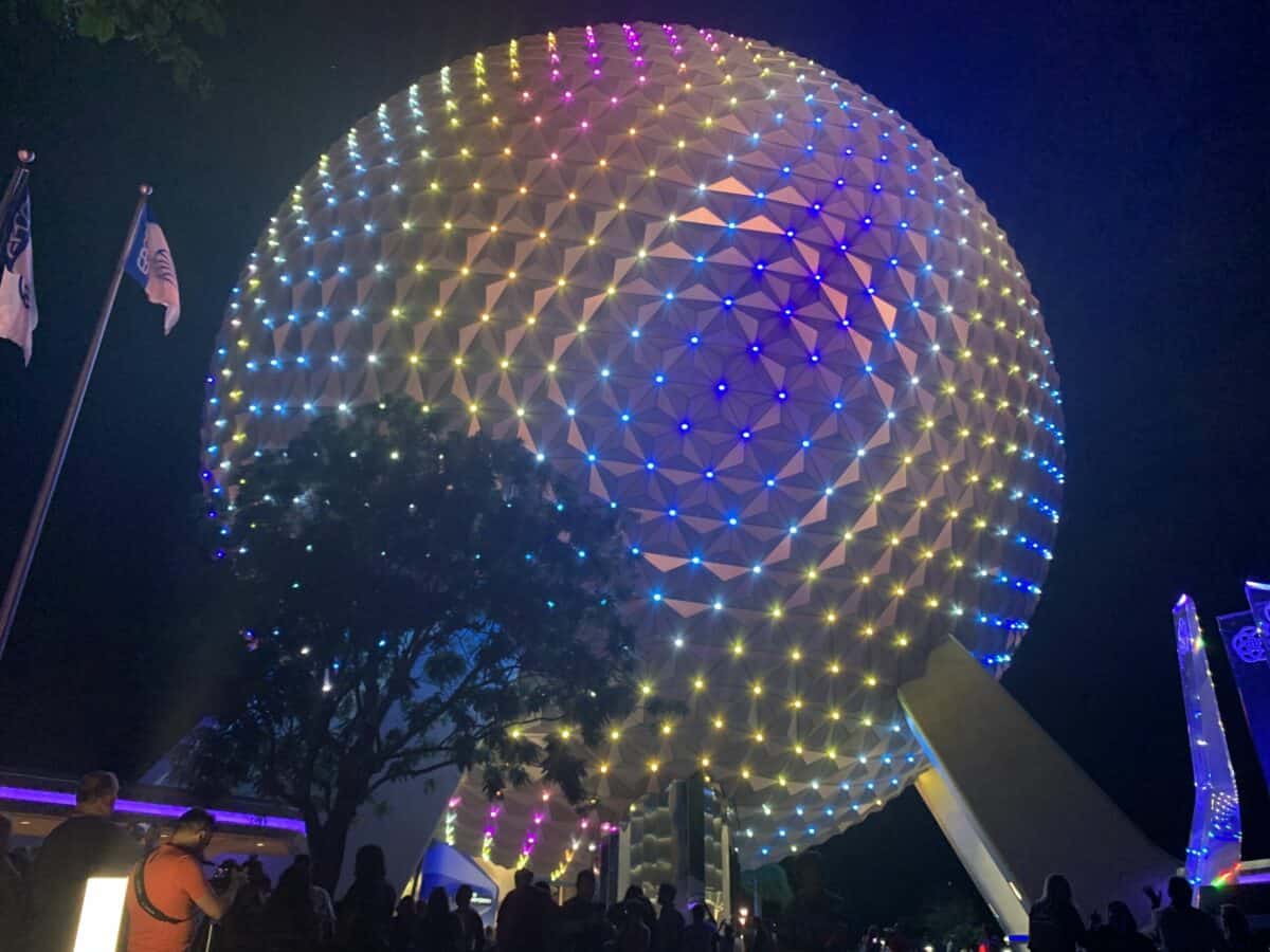Spaceship Earth glows with vibrant lights at EPCOT, colorful flags and shady trees invite Florida residents to special ticket offers.