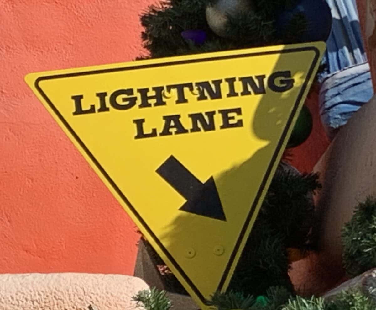 Lightning Lane yellow triangle sign with black arrow, pointing Disneyland fans to their next Genie+ adventure.