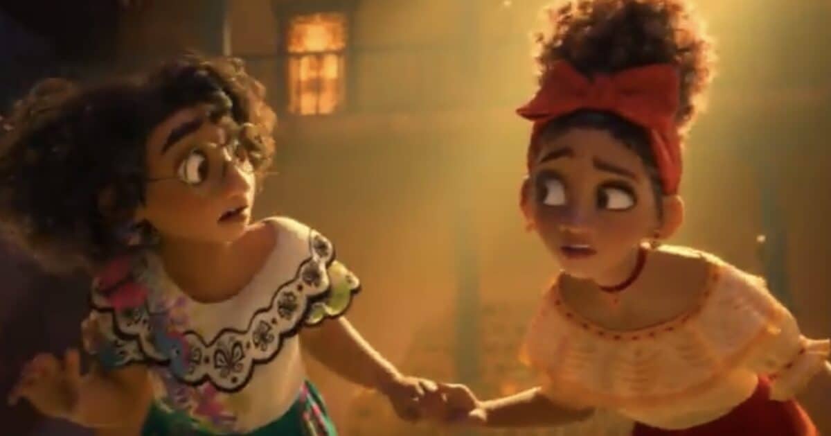 Mirabel and Isabela hold hands, looking worried inside Casita’s cozy living room, about to reveal Bruno’s secret at Encanto.