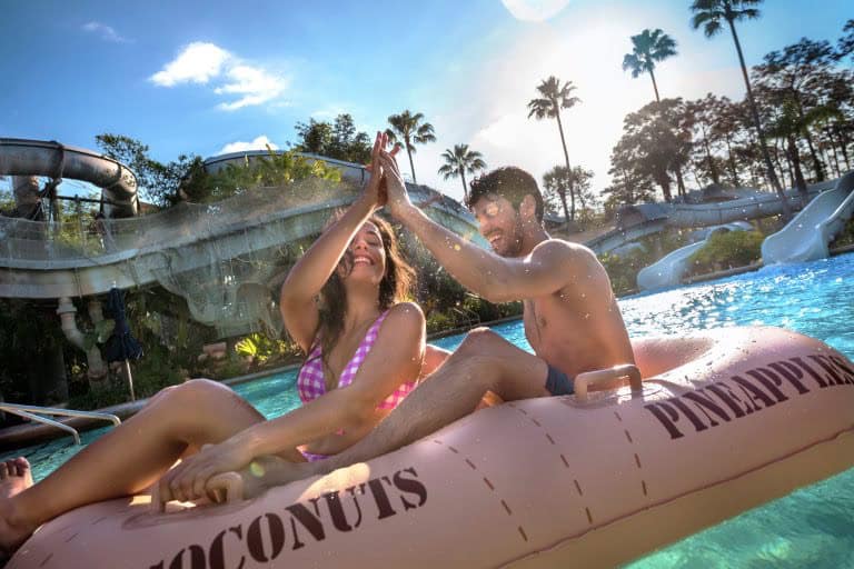 Guests in swimsuits high-five atop a pineapple float at Disney's Typhoon Lagoon pool, closed January 11–12 for maintenance.