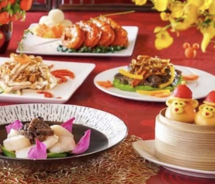 Lunar New Year at Hong Kong Disneyland features festive Chinese dishes and bear-shaped dim sum buns with red hats on a vibrant table.