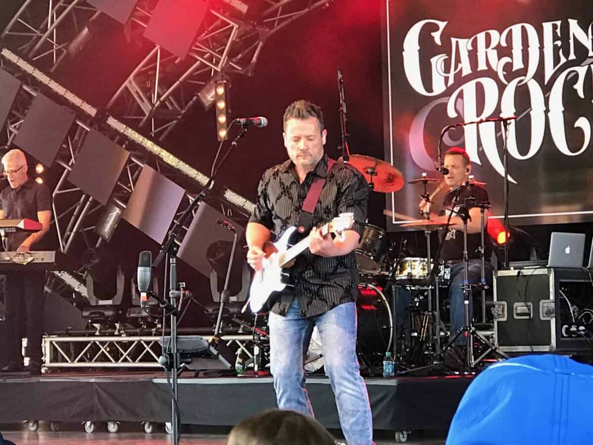 Garden Rocks Artists rock the Epcot stage, with guitar, drums, and keys lit up under the vibrant "Garden Rocks" sign.