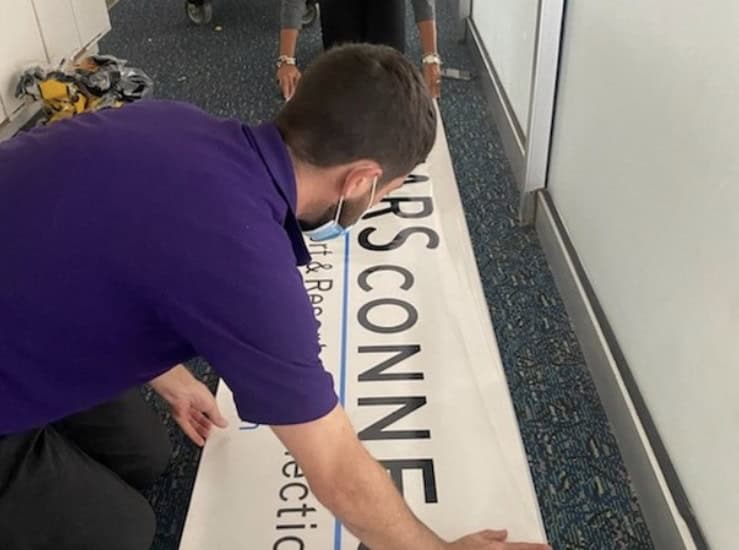 An employee arranges a Mears Connect banner in the Orlando airport, welcoming guests headed to Disney and Universal resorts.
