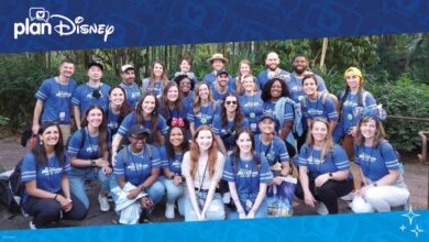 PlanDisney panelists gather outside in matching blue shirts, beaming for a group photo at a Disney Parks location.