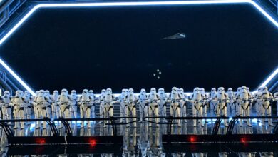 Stormtroopers stand in formation aboard a Star Wars: Galaxy’s Edge ship, with a starfield scene visible through the windows.