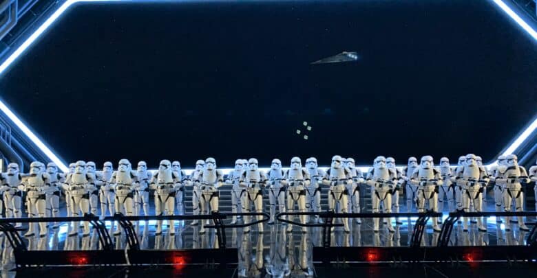 Stormtroopers stand in formation aboard a Star Wars: Galaxy’s Edge ship, with a starfield scene visible through the windows.