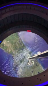 A futuristic aerial view of Florida’s coast with an exit sign above, evoking Space 220 vibes or collectible Disney trading cards.