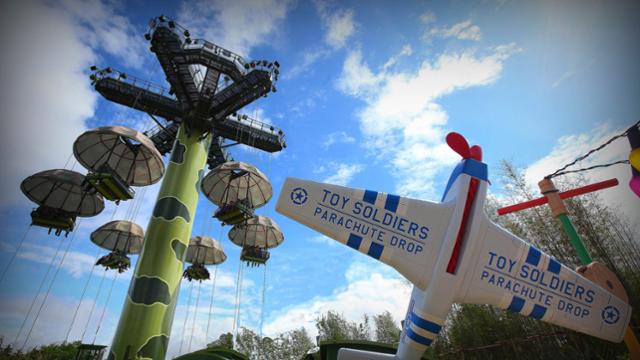 Toy Soldiers Parachute Drop ride at Disneyland Paris, with parachute seats and toy plane, set against a bright blue sky.