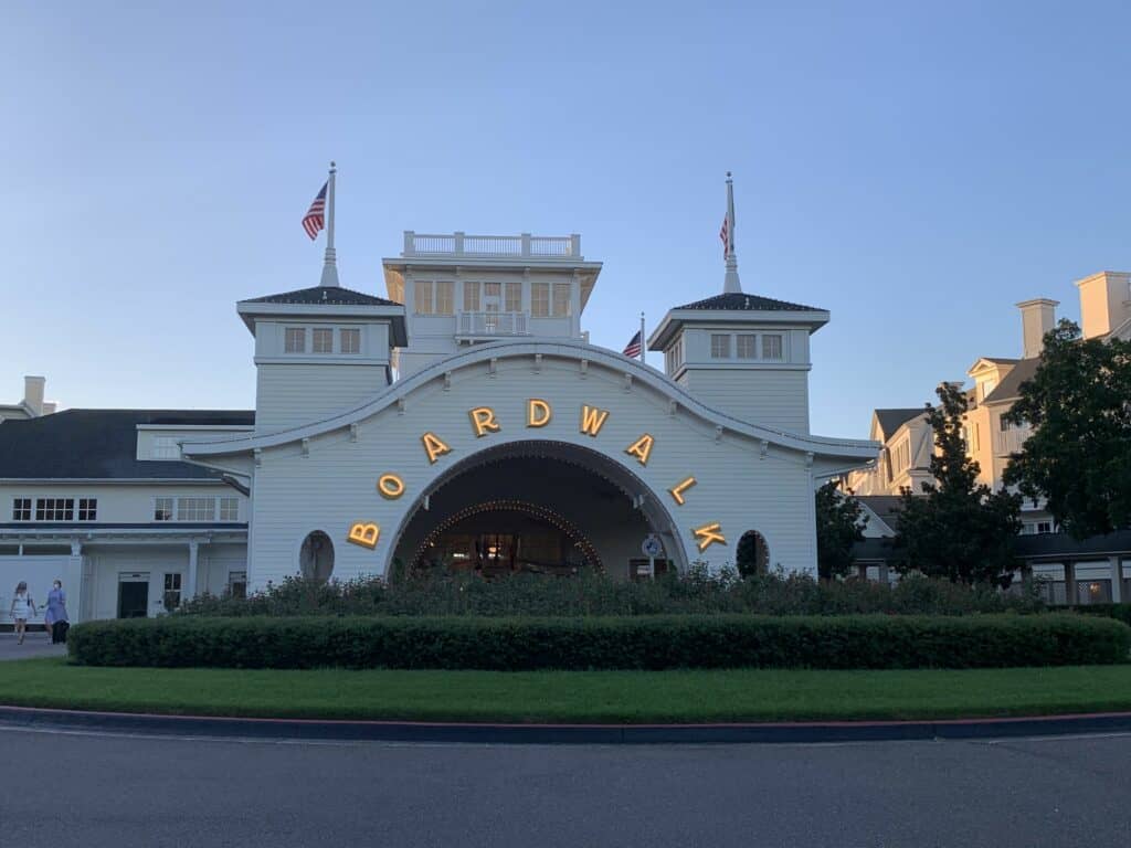 The illuminated Boardwalk entrance welcomes you with twin towers, arched gateway, and waving American flags—classic EPCOT vibes.