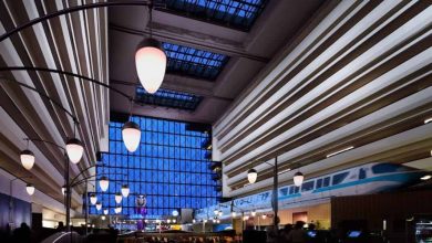 A Disney monorail glides through the vibrant Grand Floridian atrium, revealing tiered balconies and soaring skylights above.