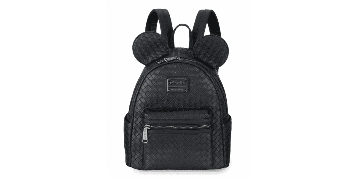 A black, textured leather backpack featuring two rounded, mouse-ear-shaped attachments at the top. The bag has a front zippered pocket with a silver zipper and an embossed brand logo above it. The straps are padded, and there are side pockets on either side.