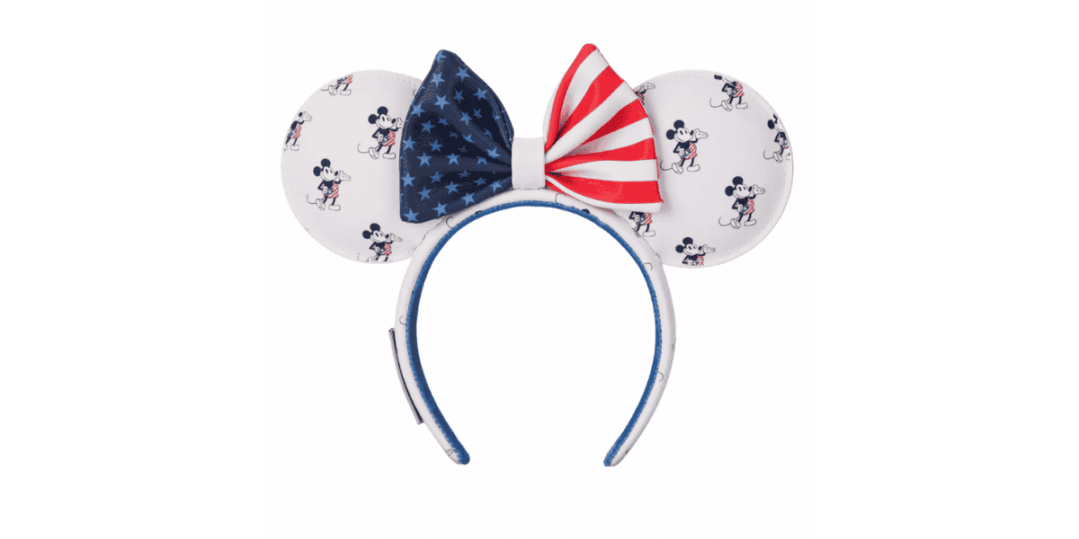 A headband featuring large, round ears adorned with a repeated pattern of a cartoon mouse in various poses. The center bow has a split design with one side displaying stars on a blue background and the other side stripes in red and white, resembling the American flag.