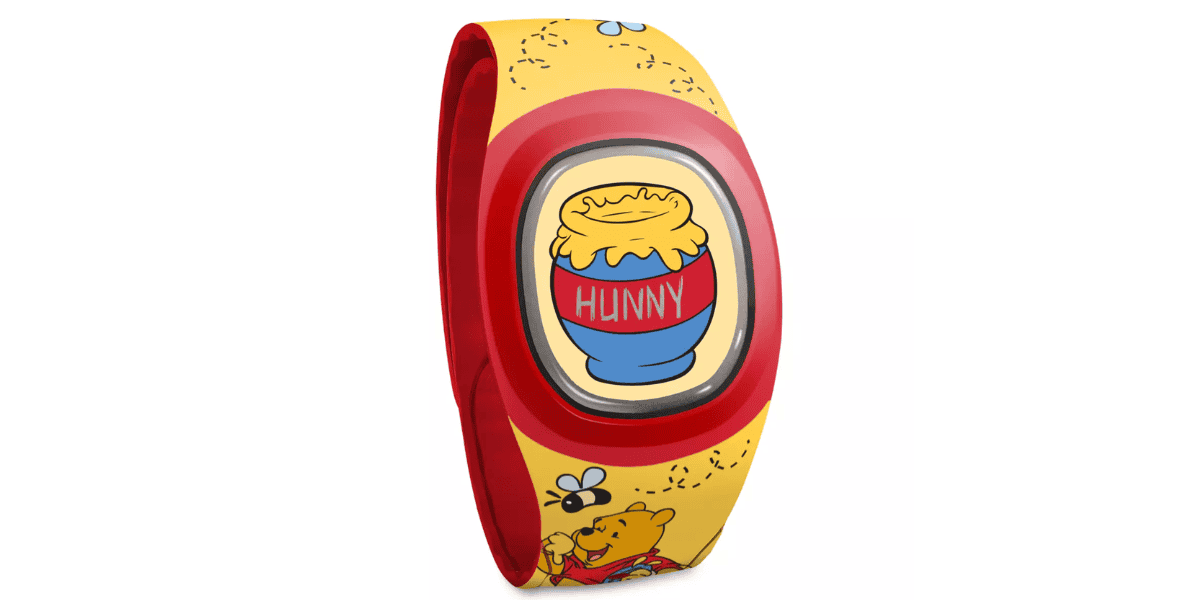 A yellow and red MagicBand featuring a design inspired by "Winnie the Pooh". The central feature is an image of a blue pot labeled "HUNNY", filled with honey. The band is decorated with bees and small illustrations of Pooh.