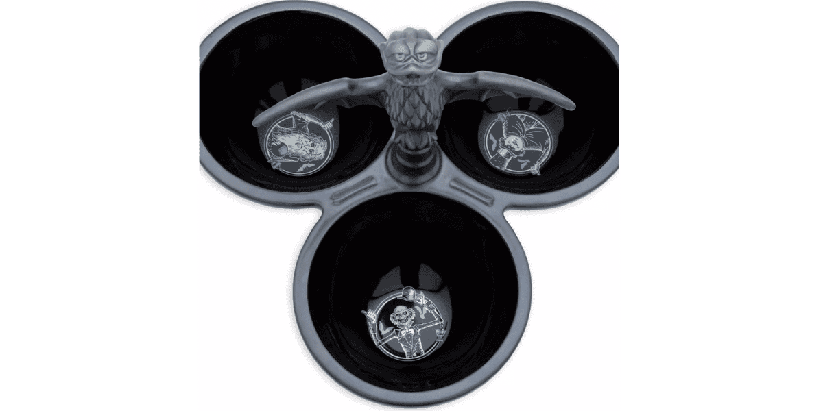 A three-sectioned black bowl from the Haunted Mansion Kitchen Collection features an owl statue perched at the center, whose wings separate each compartment. The bottom of each bowl reveals unique designs: a skeleton holding a staff, an owl with an hourglass, and a skull with a book.