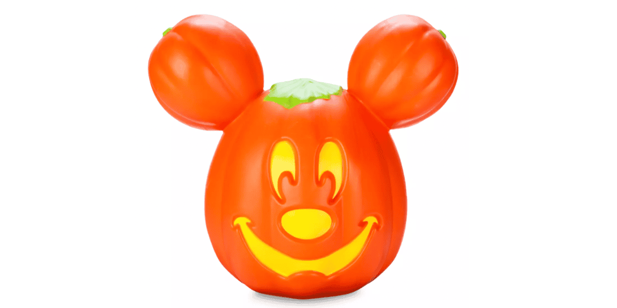 A bright orange pumpkin carved in the shape of a mouse's face with Mickey Mouse ears. The interior is lit, illuminating the mouse's happy, smiling facial features. The top of the pumpkin is green.