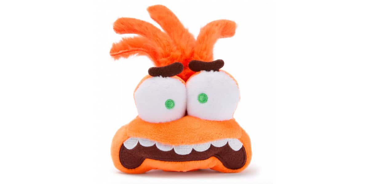 A plush toy with wild orange hair, large bulging eyes with green pupils, thick brown eyebrows, and a wide mouth showing cartoonish white teeth and a brown lower lip.
