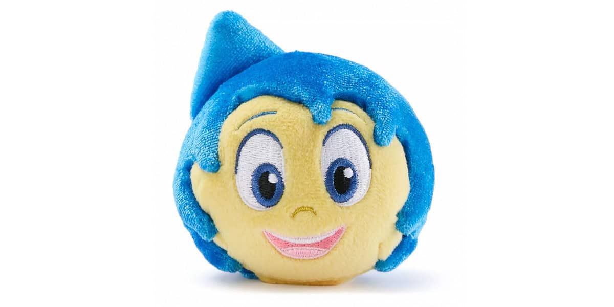 A round plush toy with a yellow face, big embroidered eyes, a pink smile, and bright blue hair shaped into a fin pointing upward.