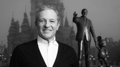 Disney fan beams with excitement in front of Cinderella Castle and iconic Walt & Mickey statue during 2023 Disney news reveal.