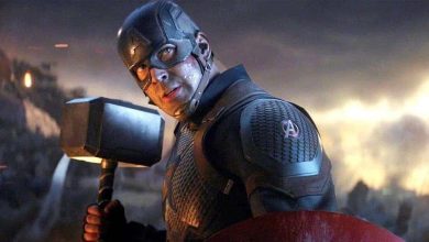 Captain America in a dramatic dark suit wields a hammer and shield on a smoky, fiery stage in an epic Disney Parks show.