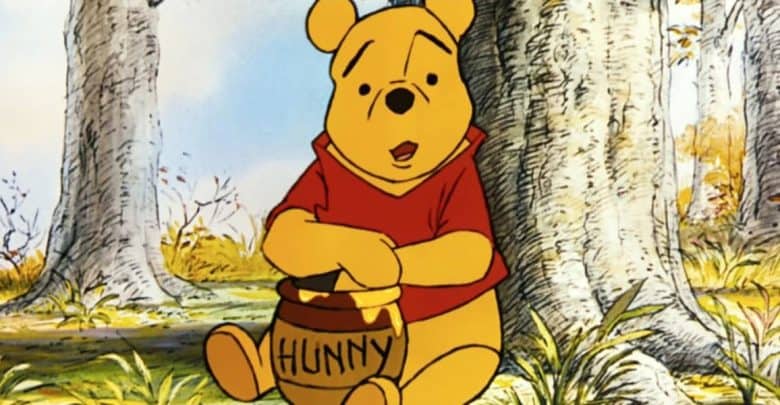 Winnie the Pooh relaxes by a tree in the Hundred Acre Wood at Disney Parks, happily holding his signature "Hunny" jar.