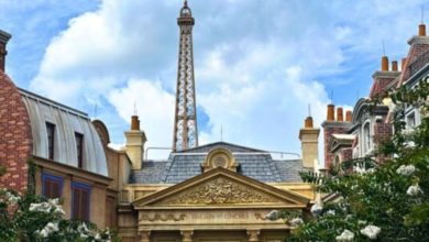 The Eiffel Tower towers above Parisian-style facades and lush trees, creating a magical backdrop like a European adventure park.