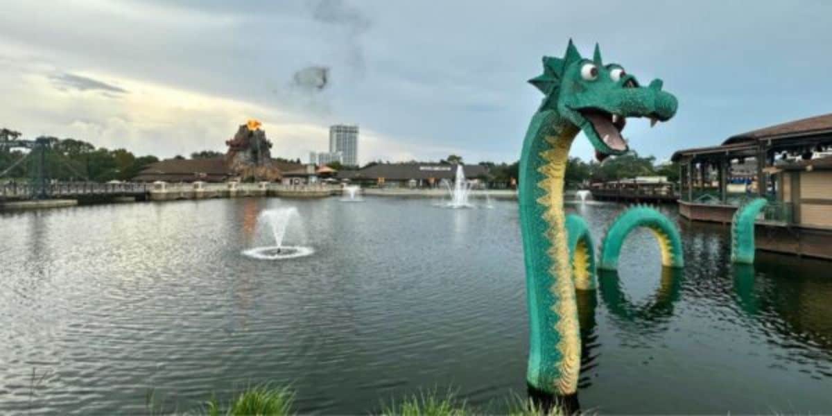 A whimsical LEGO sea serpent floats on the lake at Disney Springs, surrounded by playful fountains and vibrant shops.