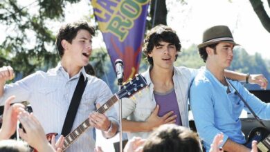 The Jonas Brothers rock the outdoor stage, jamming on guitars and singing for excited fans beneath a Camp Rock Disney backdrop.