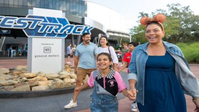 Family enjoying a sunny day, walking hand-in-hand outside Epcot’s Test Track at Walt Disney World Resort in Orlando.