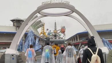 Guests walk through the Tomorrowland entrance at Magic Kingdom during the rain.