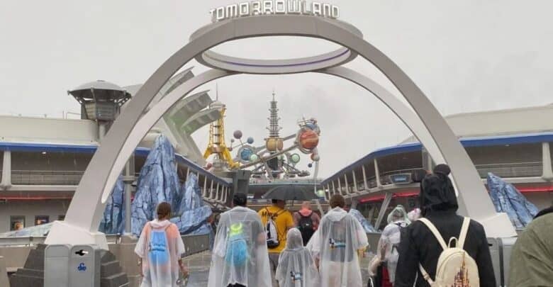 Guests walk through the Tomorrowland entrance at Magic Kingdom during the rain.